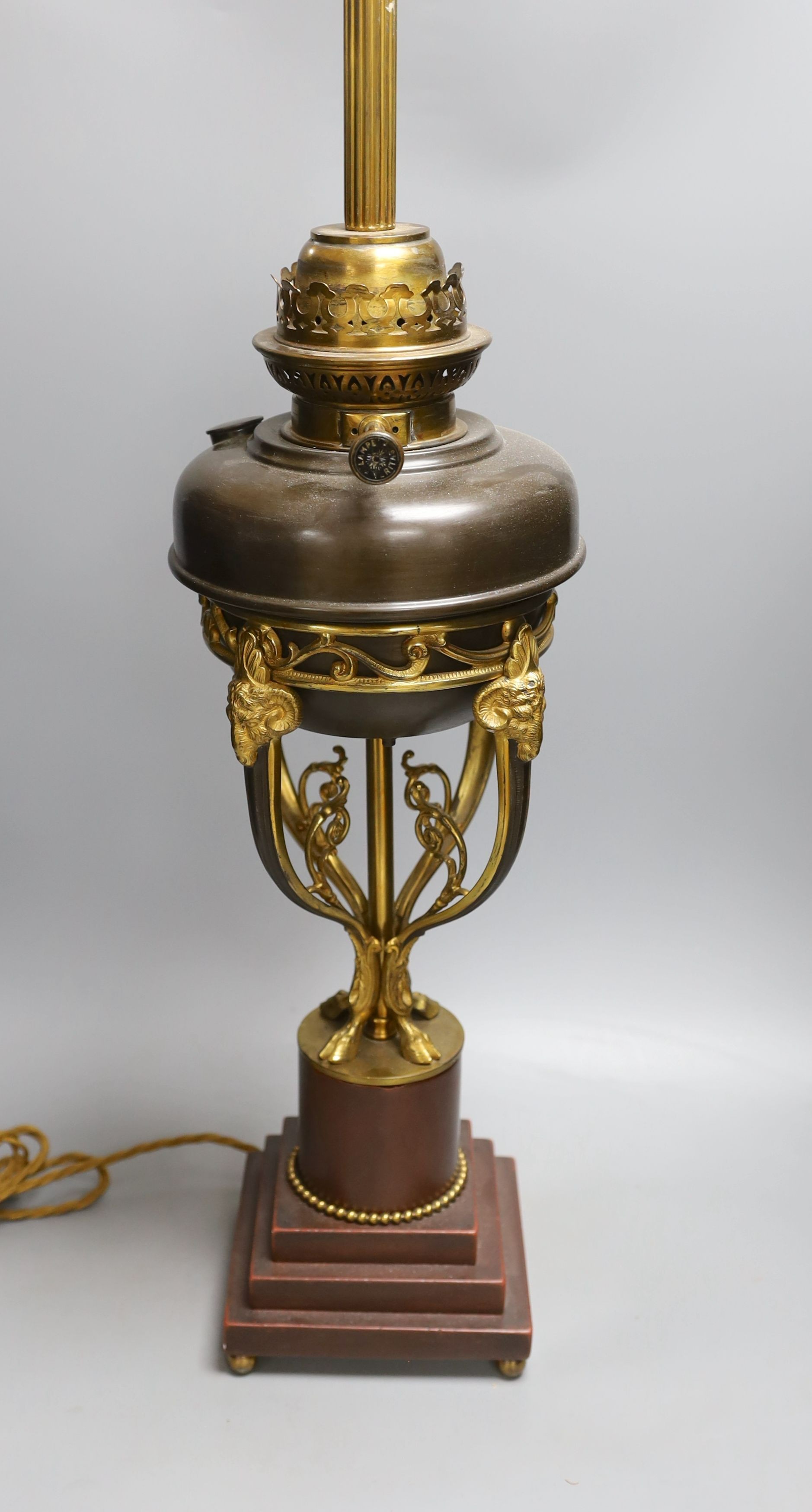 A gilt metal ‘rams head and hoof’ monopodia oil lamp, converted to electric, total height 72cm